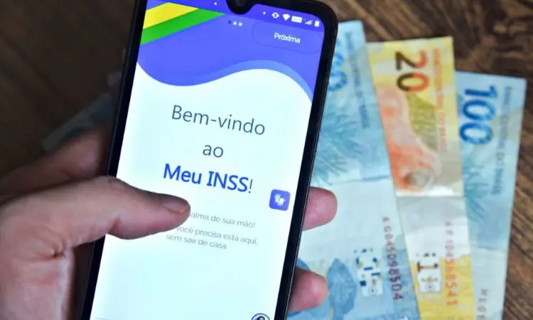 Aposentado consultando desenrola brasil consignado INSS no celular em mesa de cozinha